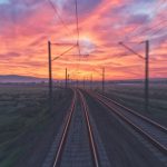 Train - empty train tracks near green grass during sunset