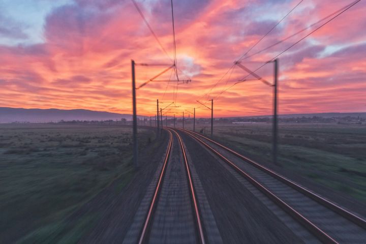 Train - empty train tracks near green grass during sunset