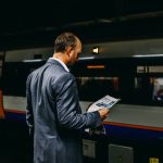 Train Ticket - man holding newspaper standing on train station