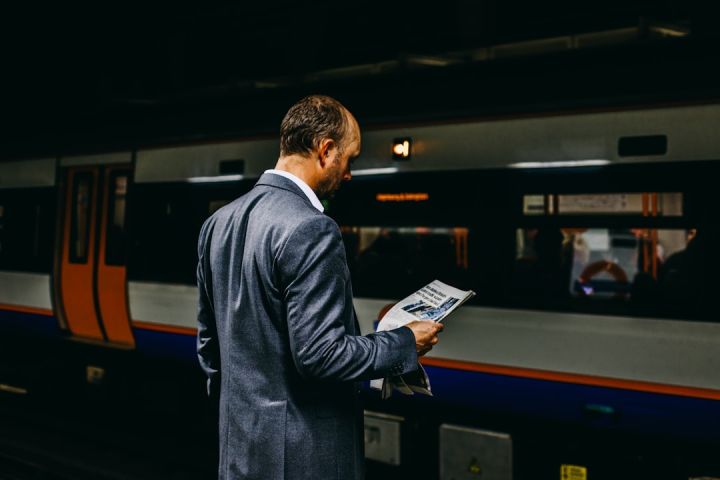 Train Ticket - man holding newspaper standing on train station
