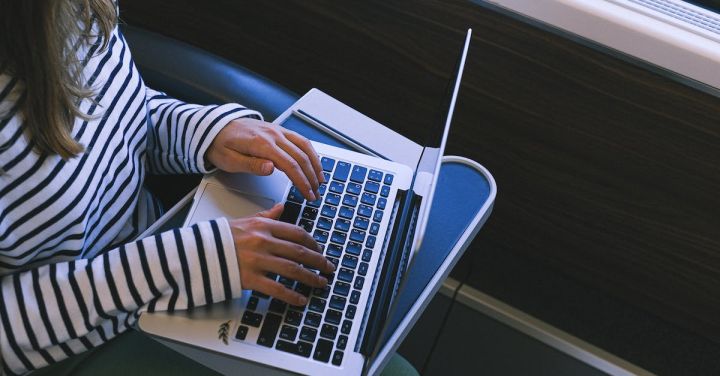 Train Seat - Person in Black and White Striped Long Sleeve Shirt Using Macbook Pro
