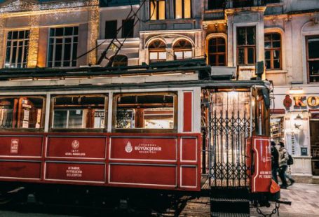Train History - Old fashioned tramway riding on rails along paved street with buildings in city