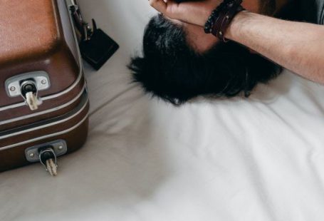 Travel Anxiety - Tired ethnic man lying on bed during relocation in new house