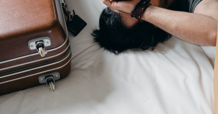 Travel Anxiety - Tired ethnic man lying on bed during relocation in new house