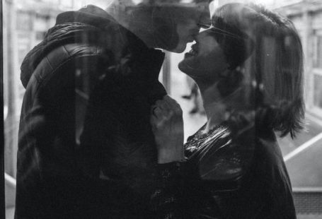 Romantic Train Getaway - Grayscale Photo of Man Kissing Woman's Nose While Standing Inside a Train