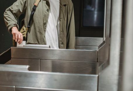 Train Ticket - Crop unrecognizable male passenger in casual clothes with backpack inserting ticket in entrance machine of automated gate while entering modern subway station