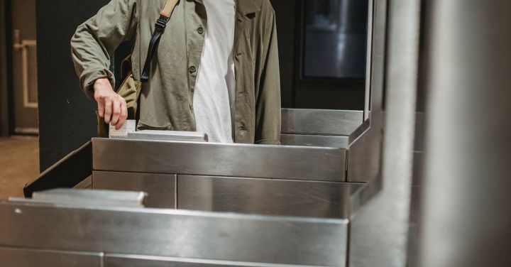 Train Ticket - Crop unrecognizable male passenger in casual clothes with backpack inserting ticket in entrance machine of automated gate while entering modern subway station
