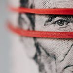 Budget Tips - Closeup of rolled United States five dollar bills tightened with red rubber band