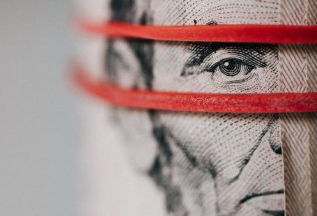 Budget Tips - Closeup of rolled United States five dollar bills tightened with red rubber band